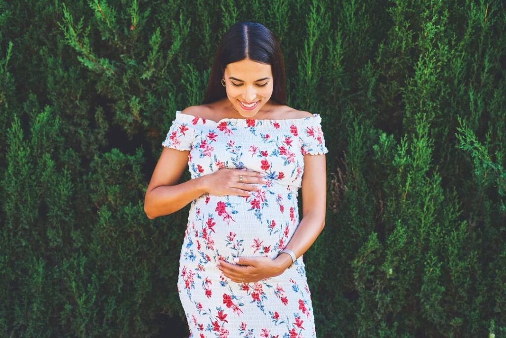 young surrogate mother holding her pregnant belly smiling