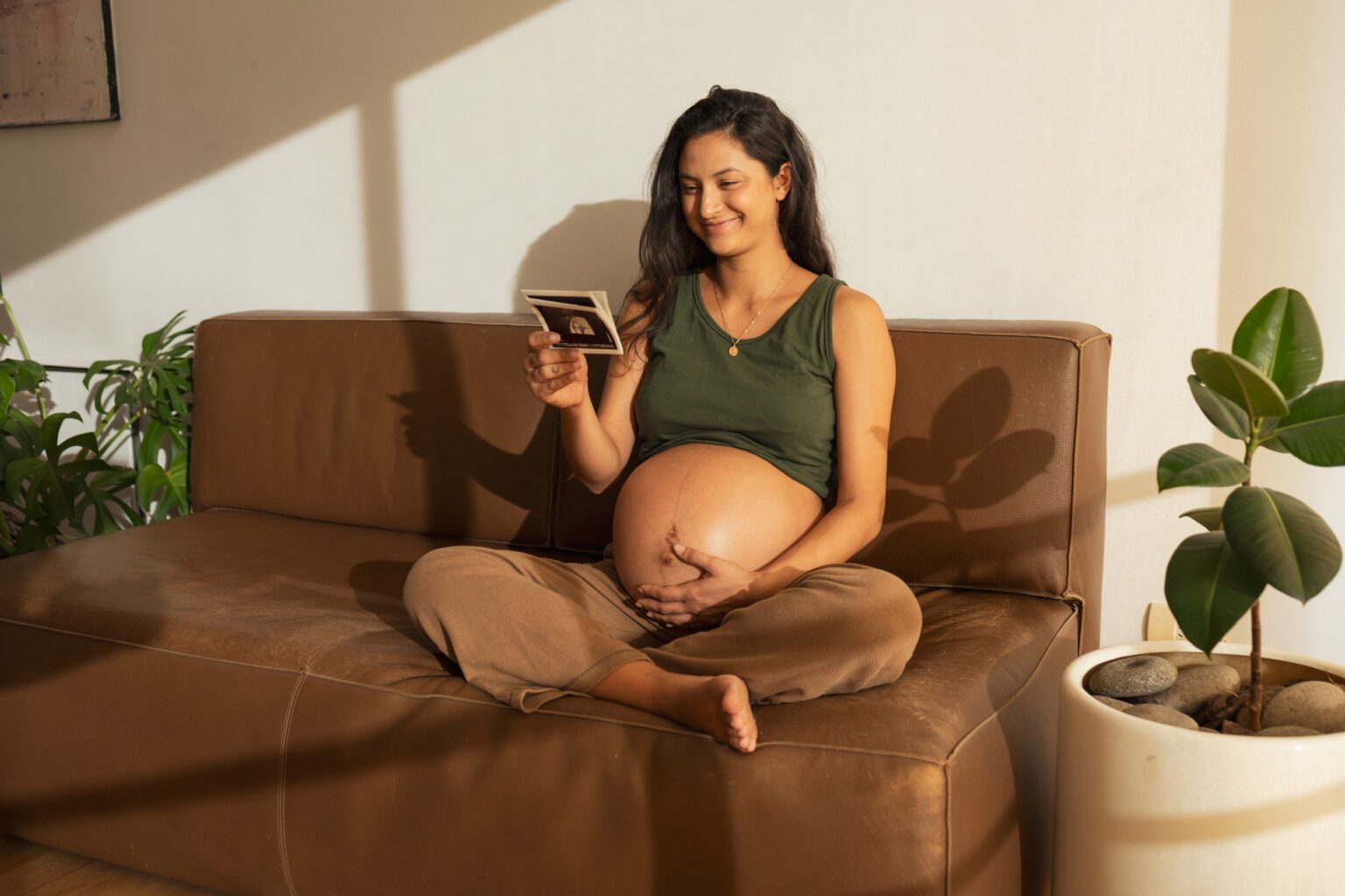 Happy pregnant woman looking at ultrasound scan at home