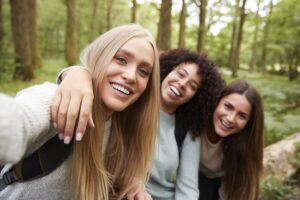 Three young adult women taking a selfie in a forest during a hike, close up