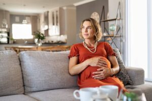 photo of a pregnant woman looking off in the distance as she grasps her pregnant belly