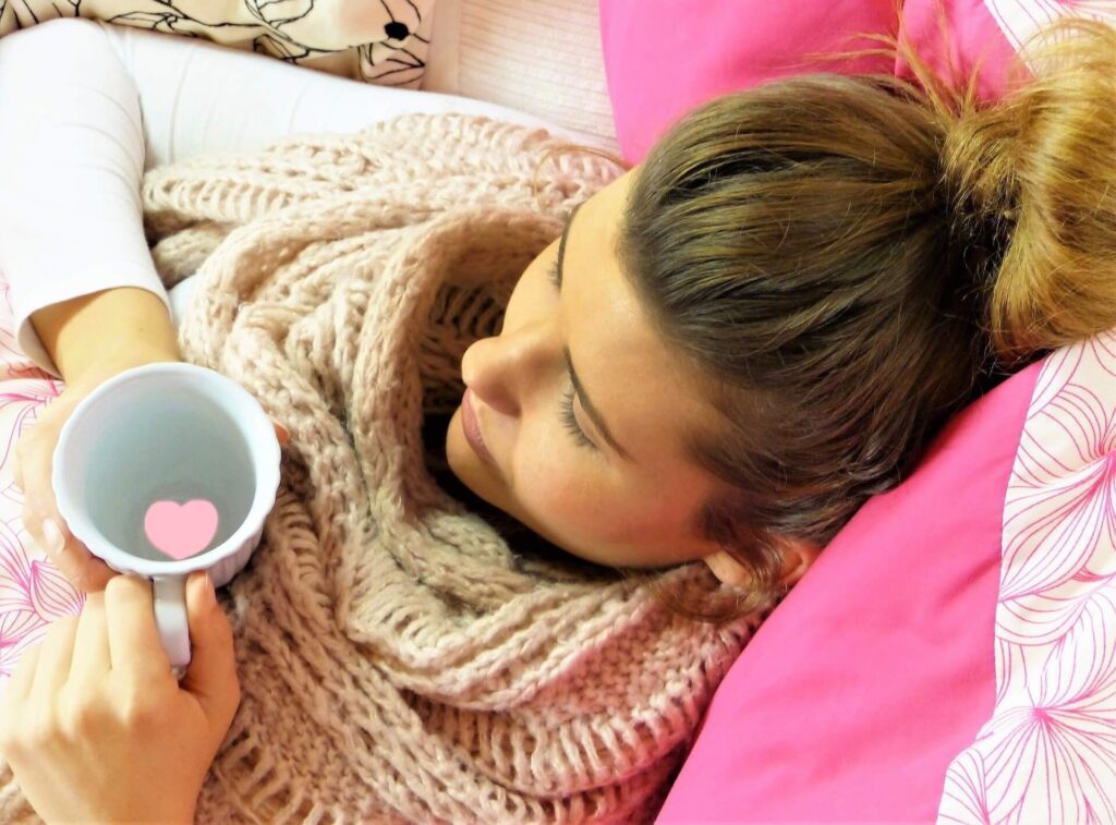female laying down drinking tea relaxing
