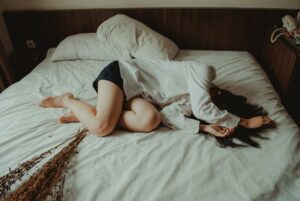 photo of a woman lying in bed looking like she is in pain