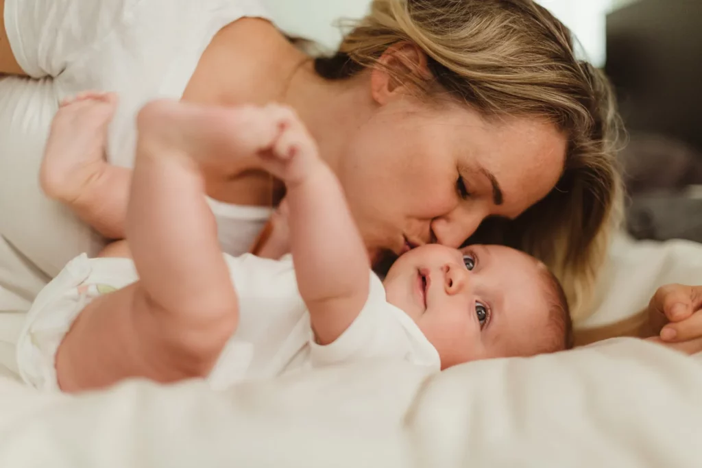mother wearing all white kissing her baby