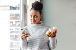 photo of female looking at her phone doing research while looking at some prescriptions
