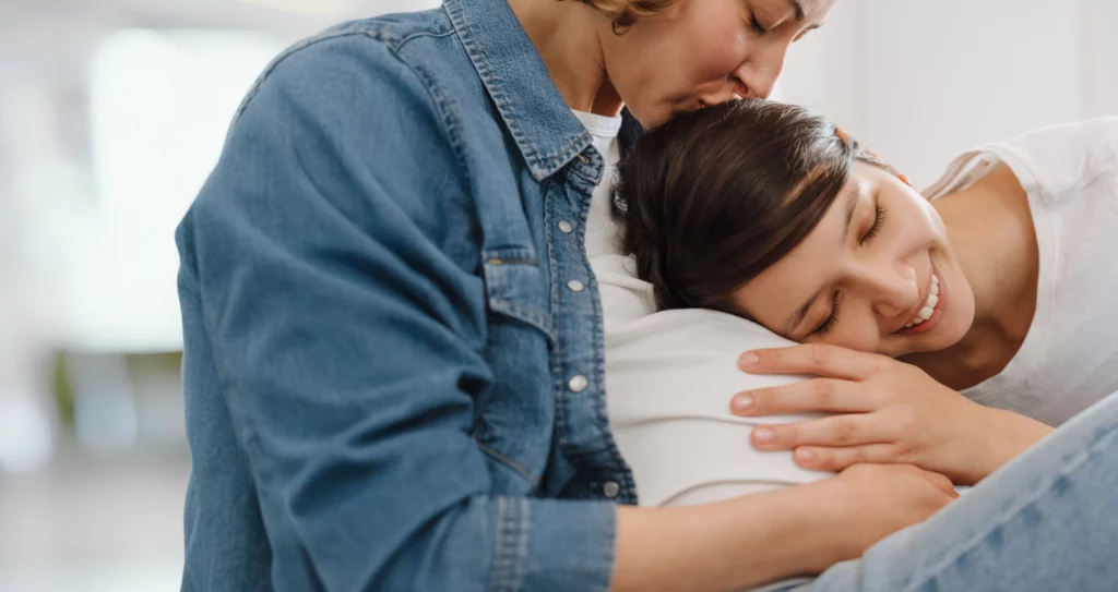 A tender moment of love and connection, as one partner gently embraces and kisses the other’s head.