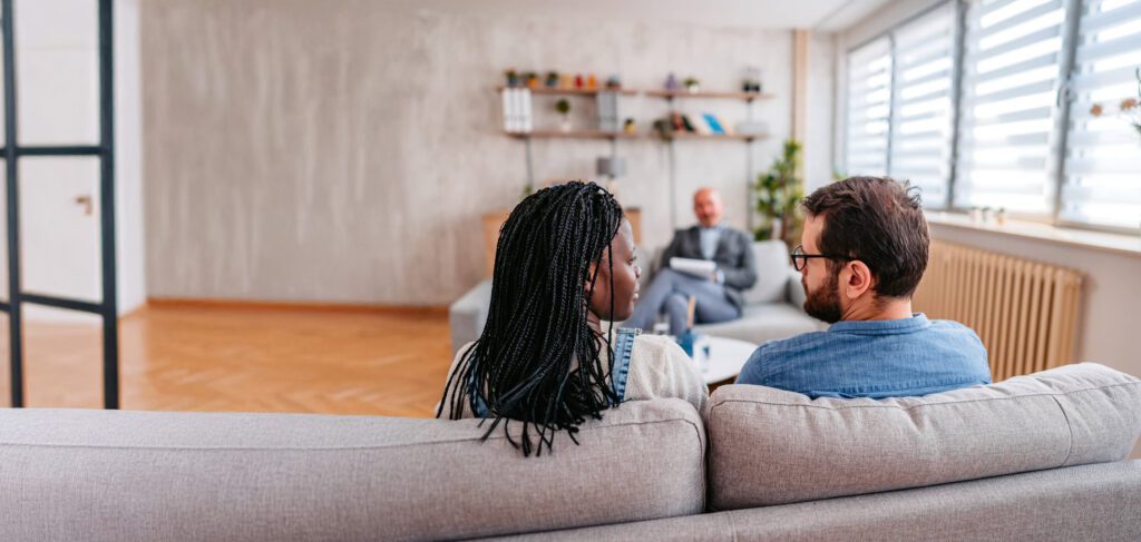 A couple sits together on a couch during a counseling session