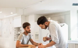 A quiet, intimate moment between two partners in a warm, modern kitchen setting.