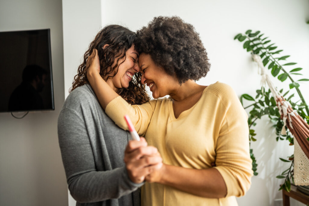 Lesbian couple holding a pregnancy test at home