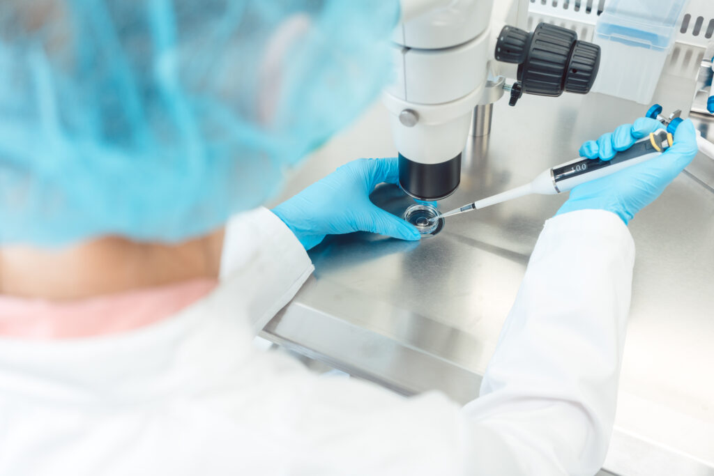Woman scientist working with pipette in laboratory dripping egg cell in solution