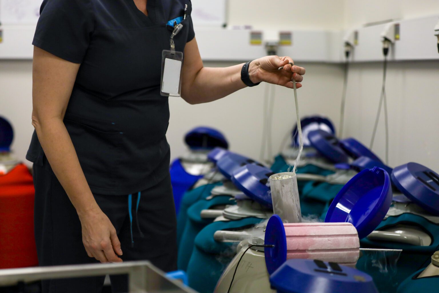 A laboratory technician carefully handles cryogenic storage containers filled with frozen reproductive cells in a specialized fertility clinic, ensuring proper preservation for future use.