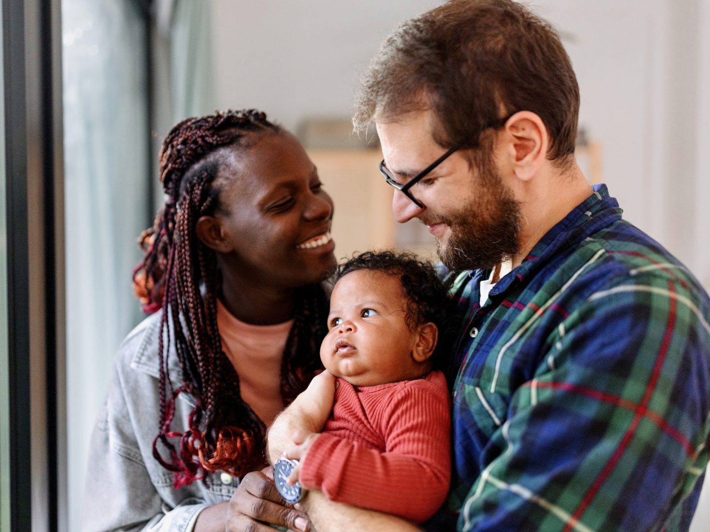 A joyful family moment is captured as two loving parents embrace their baby, radiating warmth and happiness.