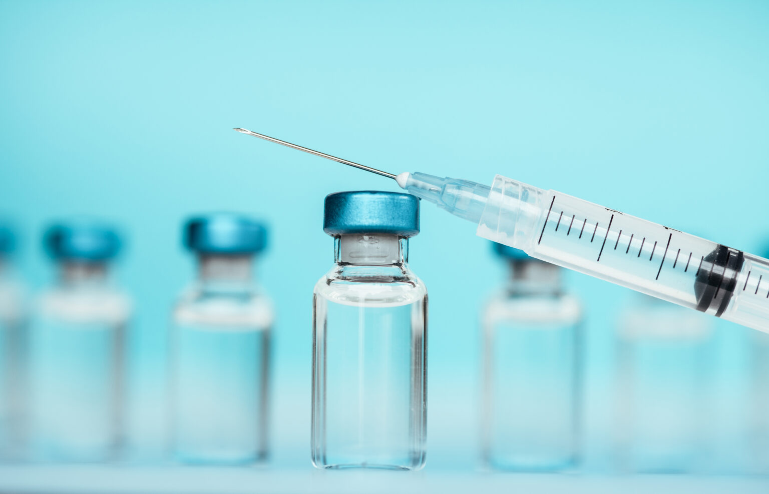 Vaccine injectable vials and syringe close up in blue tones