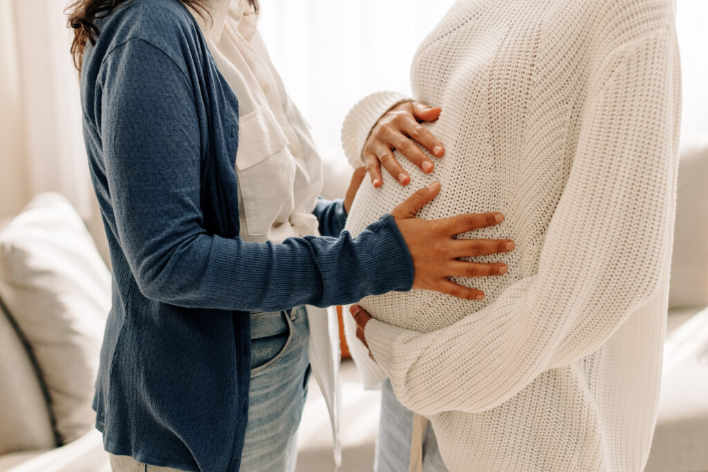 young woman touching her surrogate's pregnant bel