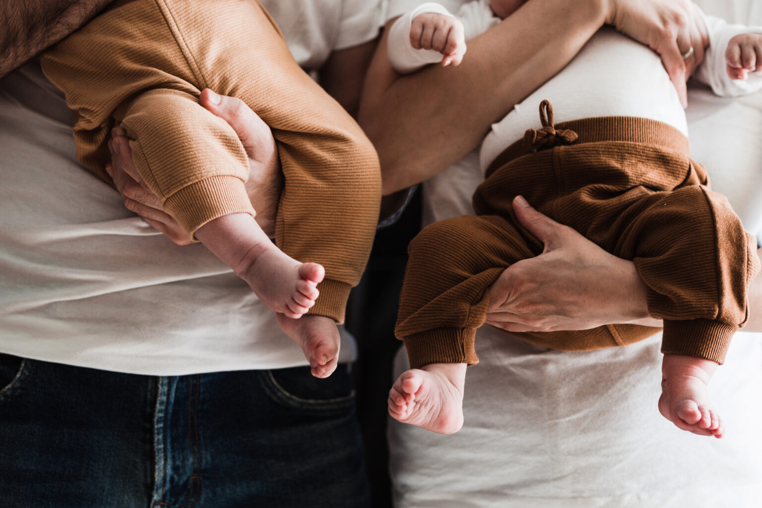 A close-up of parents holding their newborn twins, symbolizing the joy of growing a family through fertility treatments or IVF success.