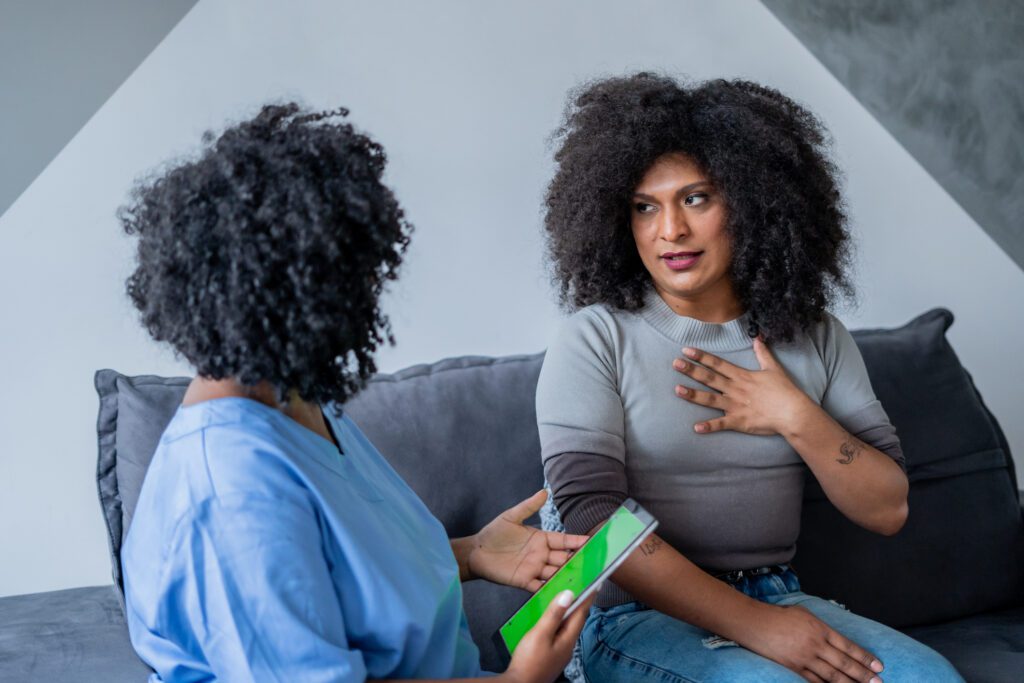 A healthcare provider and a transgender patient have a thoughtful conversation on a couch about their fertility options.