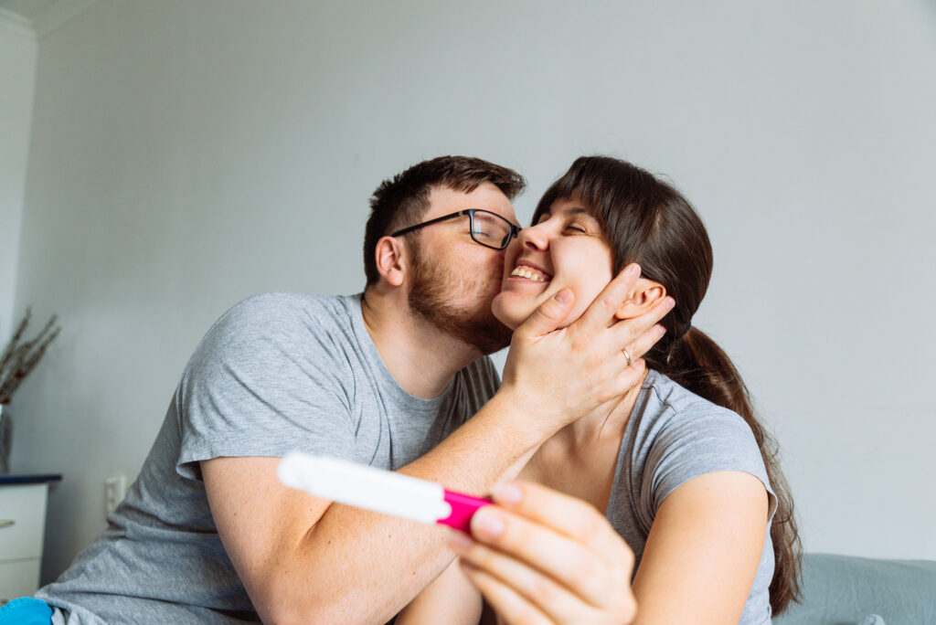 A joyful couple celebrates a positive pregnancy test, symbolizing hope and success on their fertility journey with expert medical support.