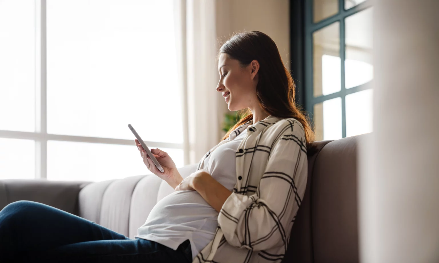 Happy pregnant mother looking at her phone