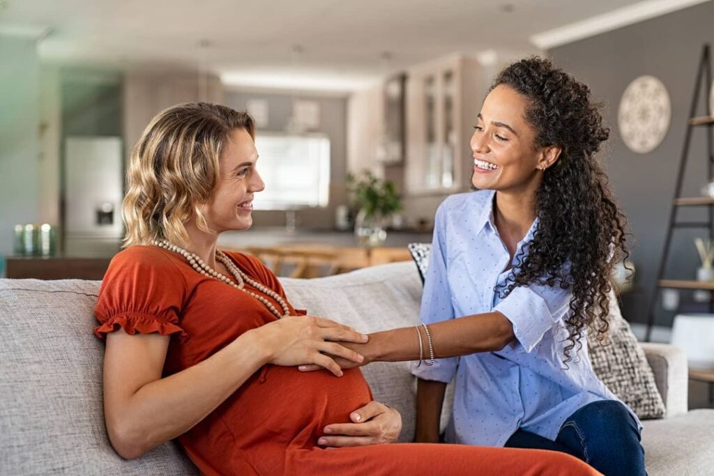 excited-friend-touching belly bump of pregnant woman