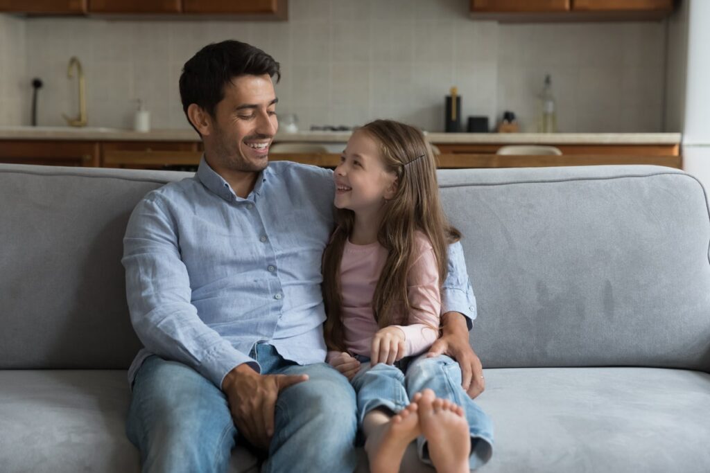 father talking with daughter on the couch
