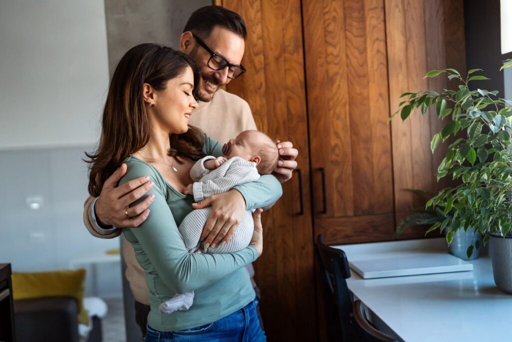 husband & wife looking down at their baby