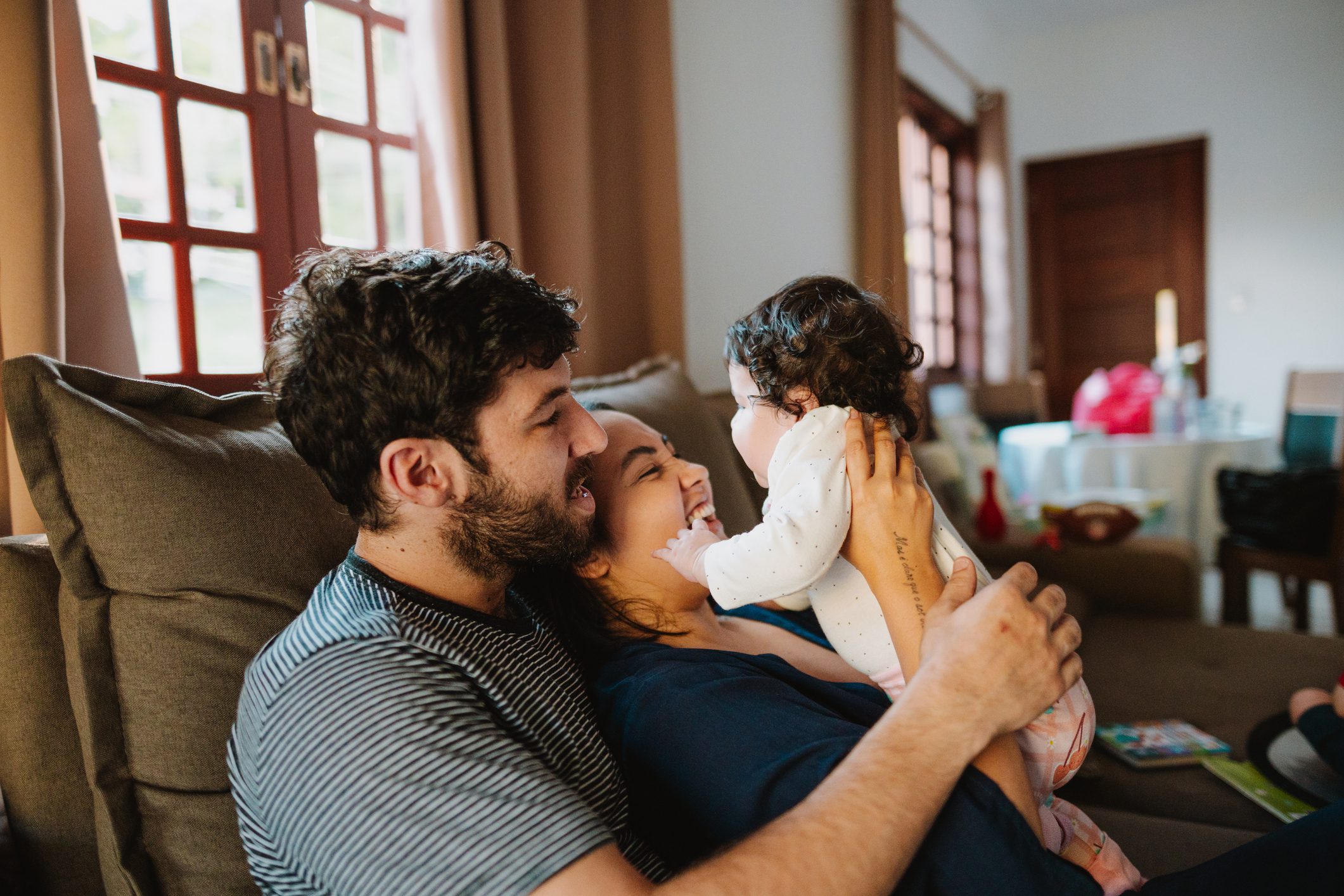 Father playing with toddler on the sofa