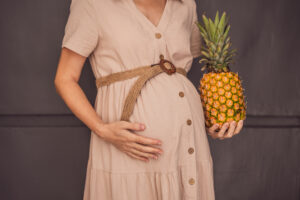 A pregnant woman’s belly, beautifully showcasing the size of her baby, likened to a pineapple. Explore the potential benefits and harms of pineapple during pregnancy and childbirth